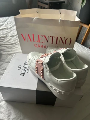 Valentino Garavani vita sneakers - Snygga vita sneakers från Valentino Garavani storlek 38 med rosa band och nitar på sidorna. Jag köpte de,men va för små för mig så aldrig gått utomhus med de.