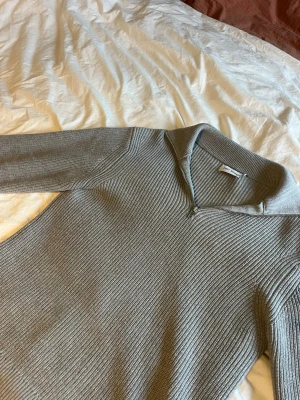 Grå stickad tröja  - Snygg grå stickad tröja med dragkedja och krage. Enkel och stilren design som passar till det mesta.