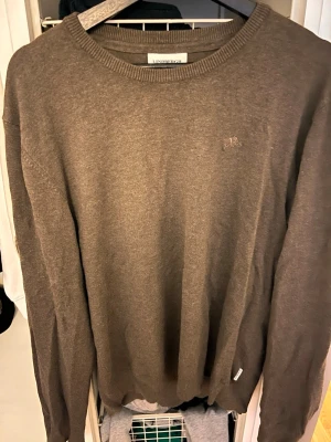 Brun tröja från Lindbergh - Snygg brun tröja från Lindbergh med rund halsringning och diskret logga på bröstet. Tillverkad i mjukt material och har ribbade muddar vid ärmslut och nederkant. Perfekt för en clean och stilren look. Storleken står xl men sitter som M