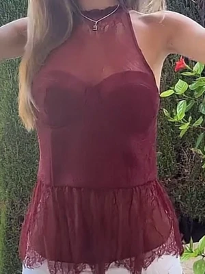 Vinröd spetslinne med volangkant - Snygg vinröd linnetopp med spetsdetaljer och volangkant nedtill. Toppen är ärmlös och har en figurnära passform med transparent mesh upptill och spets längs nederkanten. Perfekt för dig som vill ha en trendig och feminin look.