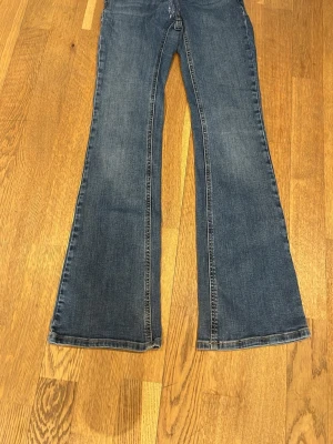 Blå utsvängda jeans från Grunt - Mörkblå jeans från Grunt. Dom har en ihopsydd söm som aldrig gått upp efter att vi sydde ihop dom. Sen har dom ett till hål som är lätt att sy igen om man orkar men det gör inte jag😅 annars är dom i bra skick
