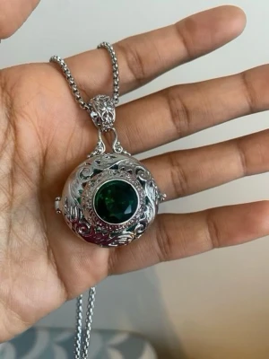 Silverhalsband med grön sten - Unikt halsband i silverfärgad metall med en stor, rund grön sten i mitten. Hänget har detaljerade ornament och kedjan är grov och stilren. Perfekt för dig som gillar statement-smycken med vintagekänsla och snygga detaljer.