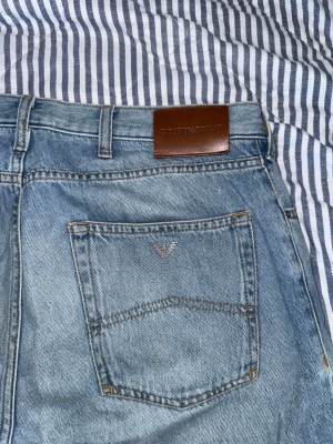 Ljusblå raka jeans - Säljer ett par ljusblå jeans med raka ben och klassisk femficksdesign. Jeansen har en lätt tvättad look med slitningar på låren och bakfickor. Perfekta för en avslappnad stil och tillverkade i denim.