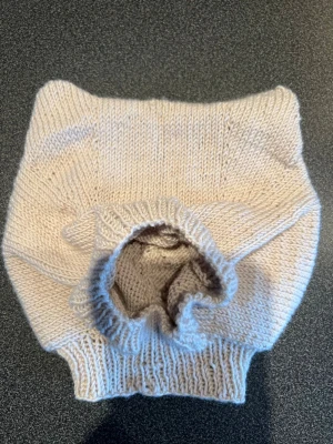 Balaclava stickad som en björn, jätte söt  - Balaclava stickad som en björn med söta små öron. Björnen är stickad i varm merinoull (Mulesingfri). Storlek ca 40 cm, passar ett barn på ca 6 månader. Bilden på den gråa balaclavan är ett kort på mönstret.