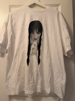 Vit t-shirt med tryck 'No Hug Zone' - Vit t-shirt med WEDNESDAY. Finns ett hål på framsidan  