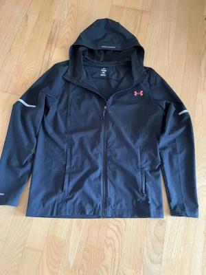 Under Armour Jacka S - Under armour jacka storlek S. Fint skick! Enda defekten är litet hål vid ena handleden som syns på bilderna. Skriv om minsta fundering!