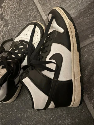 Nike Dunk High Panda sneakers - Svarta och vita Nike Dunk High sneakers med klassisk Swoosh på sidan. Skorna har högt skaft, svarta skosnören och vit sula med svart yttersula. Super snygga och passar till alla tillfällen 
