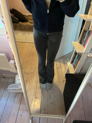Svarta bootcut jeans  - Säljer ett par snygga svarta bootcut jeans med hög midja och klassisk femficksdesign. Jeansen har en lätt tvättad look och är tillverkade i ett stretchigt denimtyg som sitter snyggt över höfterna och låren. Perfekta för dig som gillar en avslappnad men ändå trendig stil.💕