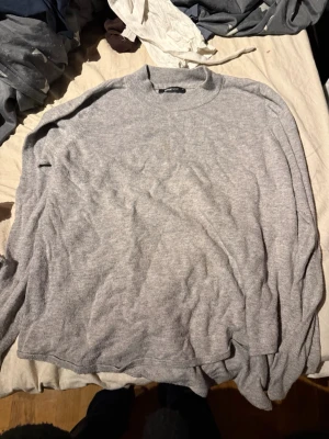 Ljusgrå stickad tröja från H&M - Mysig ljusgrå stickad tröja från H&M med rund halsringning och avslappnad passform. Perfekt för lager på lager och enkel att matcha med olika stilar. Tillverkad i mjukt material som känns skönt mot huden.