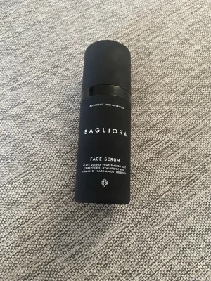 Bagliora Face Serum svart flaska - Bagliora Face Serum i en stilren svart cylinderformad plastflaska. Serumet innehåller ingredienser som svart quinoa, vattenmelon, havre, tripeptid-5, hyaluronsyra, vitamin C, niacinamide och prebiotika. Perfekt för dig som vill boosta din hudvårdsrutin. Endast använd 1 gång