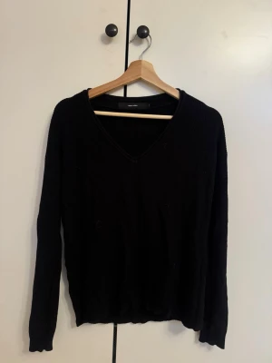 Svart stickad V-ringad tröja Vero Moda - Svart stickad tröja från Vero Moda med V-ringning och långa ärmar. Enkel och stilren design som passar perfekt till jeans eller kjol. Mjuk och bekväm, perfekt för kyliga dagar.