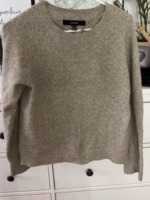 Beige stickad tröja från Vero Moda - Mysig beige stickad tröja från Vero Moda med rund halsringning och ribbade muddar vid ärmslut och nederkant. Tröjan har en enkel och stilren design som passar perfekt till lager på lager och är lätt att matcha med olika outfits.