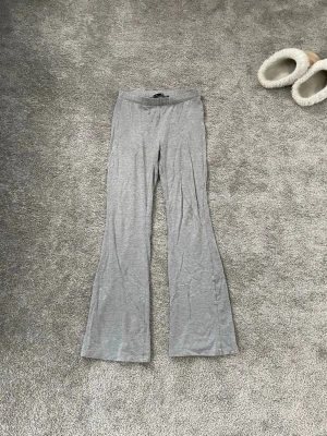 Gråa byxor från Lager 157 - Superbekväma grå byxor från 157 i storlek M. Byxorna har utsvängda ben och är gjorda i ett mjukt, tunt och stretchigt material. Enkel design utan fickor eller synliga detaljer.