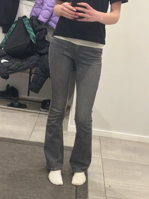 Grå bootcut jeans med stretch - Säljer ett par grå bootcut jeans med snygg utsvängd passform. Jeansen har klassiska fickor både fram och bak och är tillverkade i ett stretchigt bomullsmaterial för extra komfort. Perfekta till en avslappnad och trendig look.