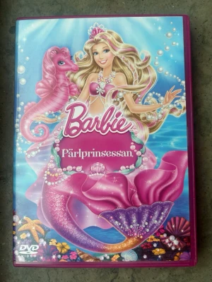 Barbie pärlprinsessan dvd - DVD-film med Barbie Pärlprinsessan. Filmen handlar om Lumina, en sjöjungfru som drömmer om ett liv som prinsessa. Hon har en magisk kraft som gör att hon kan få pärlor att dansa och lysa.  Finns på språk: Svenska, Norska, Danska, Finska, Engelska   OBS!! skivorna är begagnade så det kan förekomma repor/hairlines på skivorna, men då jag kollar igenom alla filmer jag säljer garanterar jag att alla funkar felfritt om inget annat står! :)