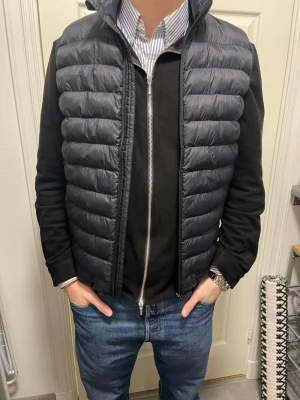 Svart dunväst med dragkedja - Snygg svart lättvikts väst  med quiltad design och hög krage. Västen har en stilren look som passar till skjorta eller hoodie. Perfekt för lager-på-lager och ger en modern vibe till din outfit. Endast använd 3 gånger, så nyskick. Nypris: 599:-
