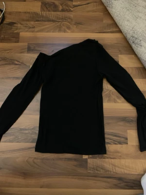 Svart långärmad tröja - En enkel svart långärmad tröja med rund hals. Tröjan har en smal passform och är tillverkad i ett mjukt, stretchigt material som passar perfekt till lager på lager eller som basplagg.