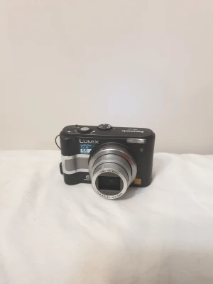 Panasonic digitalkamera svart - Säljer en svart Panasonic Lumix digitalkamera med 6.0 megapixlar. Kameran har en kompakt design med silverfärgade detaljer och en tydlig LCD-skärm på baksidan. Perfekt för dig som vill ha en smidig kamera att ta med överallt.