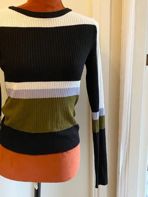 Randig ribbstickad tröja i flera färger S - Ribbstickad tröja med långa ärmar och rund halsringning. Tröjan har ett randigt mönster i olika färger. Längd: 54 cm Bystvidd: 37 cm 50% akryl, 50% viskos  Inga bilder när den sitter på mig! Katter finns i hemmet!