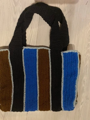 Randig virkad shoppingväska - L: 40 cm B: 14 cm Svart, blå, brun  Inga bilder när den sitter på mig! Katter finns i hemmet! 