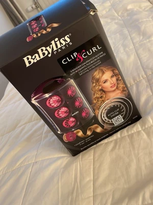 BaByliss Clip & Curl värmerullar - BaByliss Clip & Curl är ett set med 12 värmerullar i silikon som ger naturliga lockar. Rullarna är rosa och kommer i två storlekar, 17 mm och 22 mm, med auto-clip system som gör att du slipper använda hårnålar. Perfekt för att skapa snygga och enkla lockar hemma.