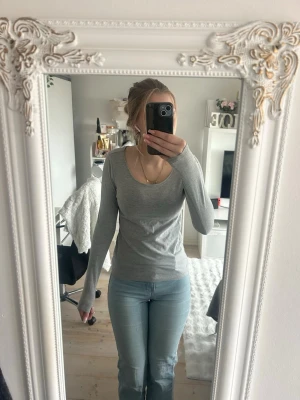 Grå långärmad topp från lager157 - En enkel och stilren grå långärmad topp från 157 med rund halsringning. Perfekt att matcha med jeans eller kjol. Materialet känns mjukt och stretchigt, vilket gör den bekväm att bära hela dagen.