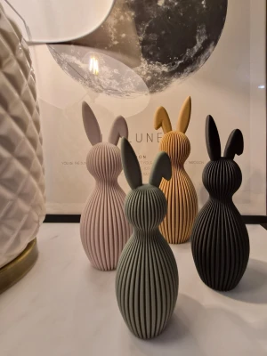 Dekorativa kaninfigurer - Fyra stilrena påskharar med räfflad yta i färgerna benvit, beige, grönl och svart. Figurerna har en modern, minimalistisk design och passar perfekt som inredningsdetalj i hemmet. Säljs som set. Största kaninen är ca 21.5 cm hög.