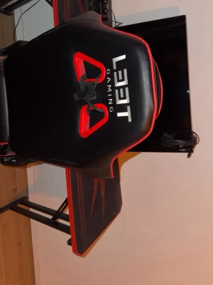 Gaming Setup, (Allt som finns på bilden) - Leet Gaming gamingstol i svart och röd färg. Stolen har hög rygg med stöd för nacke och rygg, samt justerbara armstöd. Passar för användning vid skrivbord eller gamingstation. Materialet är konstläder med vadderad sits och rygg för ökad komfort vid längre sittperioder.  Ps4 konsol, kontroll, hörlurar, tv/  datorskärm,  gaming bord och gaming stol  Fri transport inom Stockholm! Ni står ba för köpet!  
