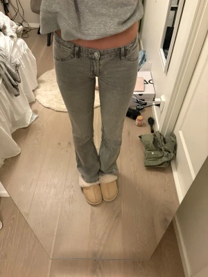 Gråa raka/bootcut jeans med låg midja - Säljer ett par gråa jeans med låg midja och raka ben/bootcut. Snygg tvätt och passar perfekt till en avslappnad look. Passar mig som är ca 164!