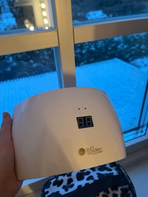 UV-lampa Sun Garden Nails vit - UV-lampa från Sun Garden Nails i vit plast med digital display. Lampan har en halvbågad form och används för att härda gelélack och nagelprodukter. Perfekt för dig som vill fixa naglarna hemma med proffsigt resultat.