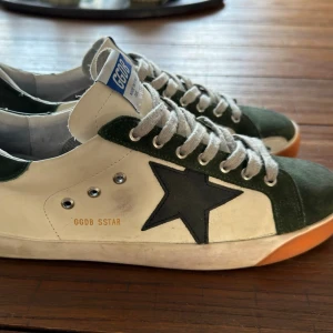 Golden Goose 2015 modell - Golden Goose Superstar sneakers i vitt/grönt. Använda men i bra skick, med den klassiska "slitna" looken som hör till märket. Bekväma och passar till det mesta. Säljs i befintligt skick utan låda. se bilder.