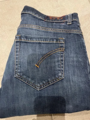 Blå jeans från dondup - Snygga blå jeans från dondup femficksmodell. Jeansen har en smal passform och raka ben, med diskreta slitningar och kontrastsömmar. Perfekta för dig som gillar en enkel men stilren look. Jeans är passar 33 32 31 i midjan
