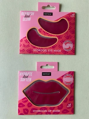 Sence hydrogel ögon- och läppmasker - Två förpackningar hydrogelmasker från Sence: en ögonmask och en läppmask. Båda är veganska och kommer i rosa förpackningar med guldiga detaljer. Ögonmasken har böjd form och läppmasken är formad som läppar. Perfekt för återfuktning och glow.