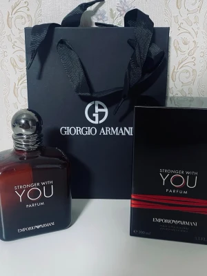 Emporio Armani Stronger With You Parfum - Emporio Armani Stronger With You Parfum i en elegant mörkbrun glasflaska med silverfärgad rund kork. Flaskan har en stilren design och kommer med originalförpackning och exklusiv presentpåse från Giorgio Armani. Perfekt för dig som gillar lyxiga dofter.