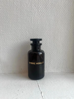Louis Vuitton Ombre Nomade parfym - Exklusiv parfym från Louis Vuitton, Ombre Nomade. Flaskan är mörkbrun i glas med guldfärgad text och har ett elegant, rundat lock med LV-logga på toppen. Lyxig design som verkligen sticker ut på parfymhyllan.