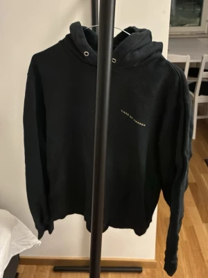 Svart hoodie från Tiger of Sweden • Herr • M (något mindre i storlek) - Snygg svart hoodie från Tiger of Sweden med minimalistisk logga på bröstet. Klassisk modell med huva och metallöljetter för snören (obs, snörena sitter inte i men skickar med de). Använt en del men den är fortfarande fin. Lite liten i storleken, så skulle satsa på denna ifall jag vanligtvis bär storleken S. 