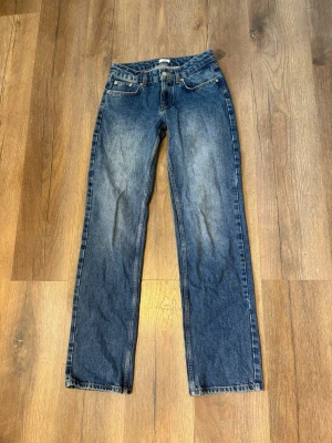 Blå raka jeans från Nelly - Klassiska blå jeans från Nelly med rak passform och fickor. Jeansen har en snygg tvätt med lätt slitning framtill och bak, samt Nelly lapp på linningen bak. Tillverkade i slitstarkt denimtyg, perfekta för en avslappnad och tidlös stil. Nyskick så inga defekter alls! Kom gärna med prisförslag om det behövs!💓🌸