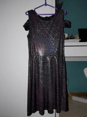 Lila glittrig klänning med cold shoulder  - Lila glittrig klänning med cold shoulder. Färgen har gått bort life efter några tvättningar. Skönt för en kväll ute med dina vänner