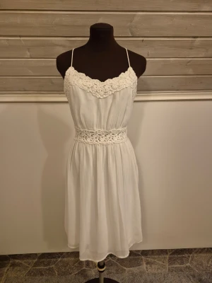 Vit spetsklänning - Söt vit klänning med smala axelband och fina spetsdetaljer vid byst och midja🤍💎☁️Dragkedja i ryggen. Minidress om man är lång, annars midi. Knappt använd och i fint skick. Det är bara att skriva om man har frågor!😊💖