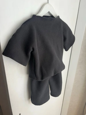 Mörkgrått loungewear-set i bomull - Säljer ett handsytt mörkgrått loungewear-set med oversized t-shirt och matchande shorts. Setet är gjort i ett mjukt, ribbat ekologiskt bomullstyg som känns riktigt skönt mot huden. Passar 12-18m, 86