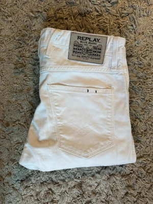 Vita jeans från Replay - Säljer ett par vita jeans från Replay med klassisk femficksdesign och snygg patch bak i midjan. Jeansen har raka ben och är tillverkade i mjuk bomull för skön känsla. Perfekta för dig som vill ha en clean och stilren look.