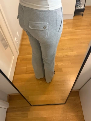 Grå juicy couture byxor  - Hej!! 🌸 Jag säljer mina gråa juicy couture byxor med raka ben, resår i midjan och snören. Byxorna har två stora fickor fram och bakfickor med knapp. Perfekta för en chill dag hemma eller när du vill vara bekväm. Mjukt material som känns skönt mot huden. Har använt fåtal gånger! Skriv ifall ni är intresserade eller har frågor!💗