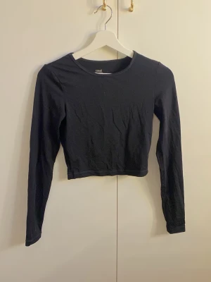 Svart croppad långärmad träningströja Casall - En svart croppad långärmad träningstopp från Casall. Enkel och stilren design med rund halsringning. Tillverkad i mjukt material som känns skönt mot huden. 