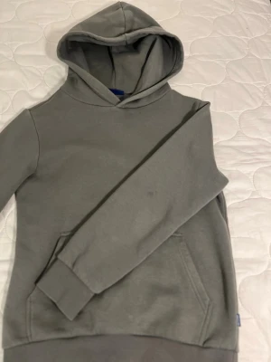 Grå hoodie från Only & Sons - En stilren grå hoodie från Only & Sons med klassisk huva och känguruficka framtill. Tillverkad i mjukt material som känns skönt mot huden. Perfekt för dig som gillar en enkel och clean look. Långa ärmar med muddar och avslappnad passform.