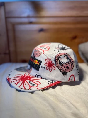 Redbull Racing keps men japanskt mönster! - Red Bull Racing keps i riktigt fint nytt skick 🔥 Vit med unikt mönster inspirerat av japanska motiv – sticker verkligen ut! • One size (justerbar) • Lätt och bekväm • Perfekt till sommaren eller för en sportig look • Äkta Red Bull Racing Endast testad en gång, inga fläckar eller skador. Skriv om du har frågor eller vill ha fler bilder 😊 