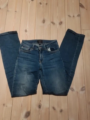 Blå jeans från Vero Moda - Säljer ett par klassiska blå jeans från Vero Moda. Jeansen har fem fickor, normal midja och smal passform. Tillverkade i stretchigt denimtyg. Perfekta till en avslappnad look och passar till det mesta. Storlek 26/32 antingen Xs eller Xss