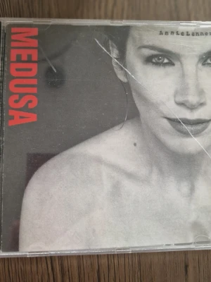 CD Medusa Annie Lennox - CD-skiva med albumet Medusa av Annie Lennox. Omslaget är svartvitt med röd text och plastfodral. På baksidan finns låtlista med tio spår, bland annat 'No More I Love You's' och 'A Whiter Shade of Pale'. Perfekt för dig som gillar klassisk pop och samlar på CD-skivor.