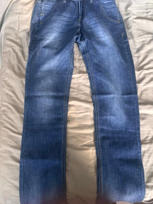 Blå raka jeans med slitningar - Säljer ett par slim fit blå jeans med snygga slitningar