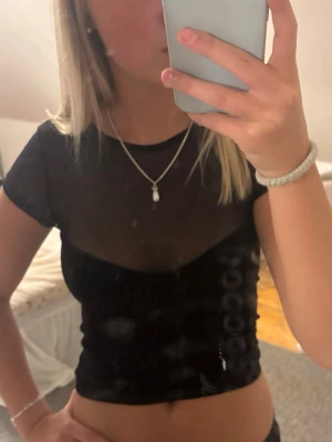 Svart mesh croppad topp - Säljer en svart, croppad mesh topp med korta ärmar. Toppen är genomskinlig och har en tight passform som ger en trendig look. Köptes på stradivarius i grekland. Storlek xs, men liten i storlek 