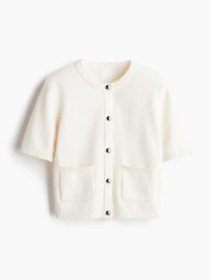 Vit kortärmad kofta med fickor - Stilren vit kofta med korta ärmar och rund halsringning. Koftan har ribbade kanter, två framfickor och knäpps med silvriga knappar framtill. aldrig använt men råkat klippa bort lappen.